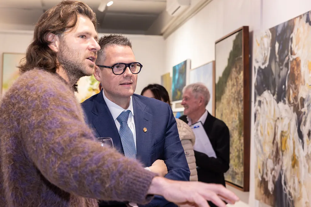 An artist talking to visitors at an opening
