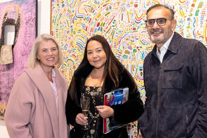 Three guests in front of a painting